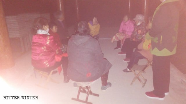Cristianos de la tercera edad se reúnen en un quiosco fuera de la villa mientras está oscuro afuera.