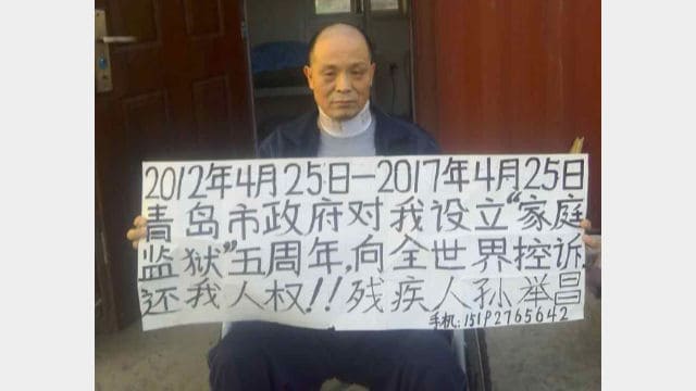 El 25 de abril de 2017, Sun Juchang sujeta un letrero en su hogar