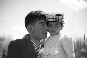 Un hombre carga cariñosamente a su hija, vestida para una celebración familiar