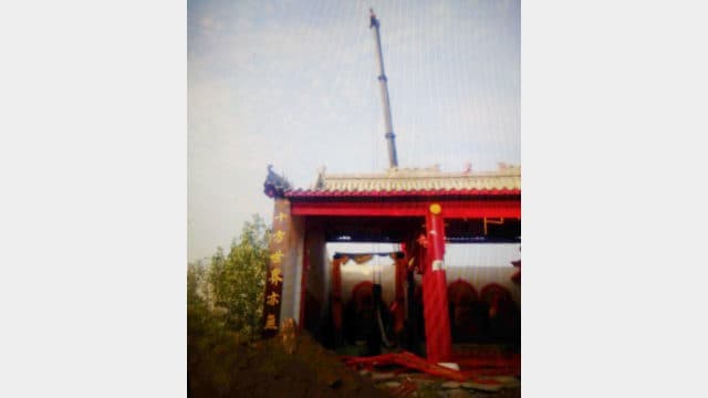 Una grúa levanta la estatua budista mientras el vestíbulo está siendo demolido.