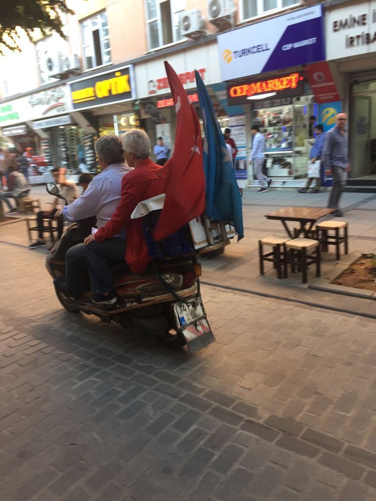 Motociclistas uigures flameando tanto la bandera turca como la turquestana en la parte trasera de su bicicleta.