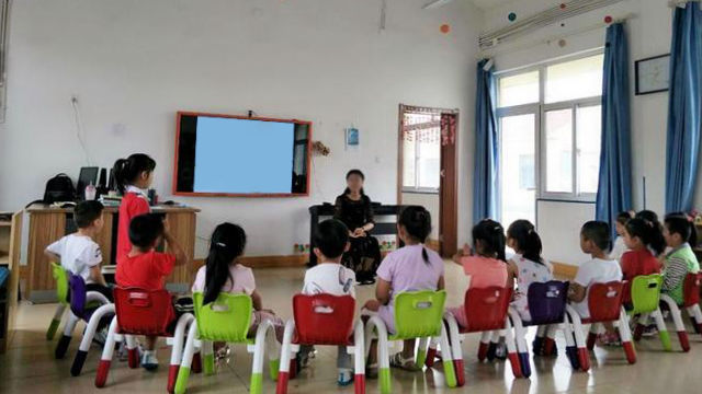 Una maestra de kínder habla con los niños en una clase.