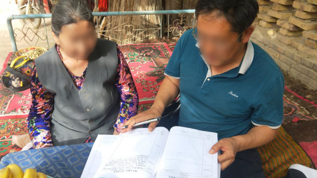 funcionario del gobierno en Xinjiang le pide a dos ancianos que lea los materiales