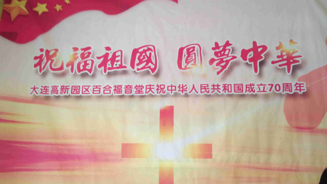 Póster propagandístico de “Oda a la Patria” y “Cumpliendo el sueño de China” exhibido en la entrada de una iglesia.