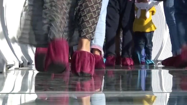 Los turistas portan cubrezapatos mientras atraviesan el puente sobre un cristal especialmente programado, que se “hace añicos” y se “astilla” bajo sus pies.
