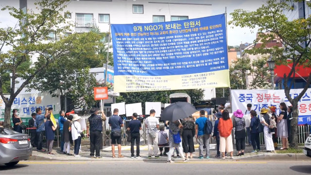 Organizados por el PCCh, familiares de miembros de la IDT y manifestantes profesionales protestan frente a la entrada de las instalaciones de la IDT en Seúl.