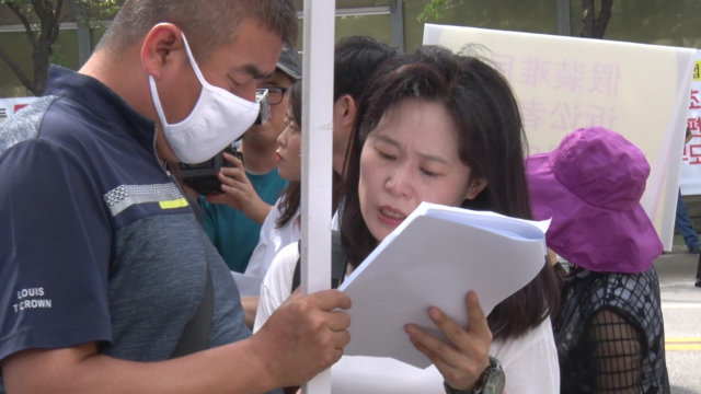 Durante una manifestación, la Sra. O Myung-ok está revisando un manuscrito con un familiar de un creyente de la IDT.