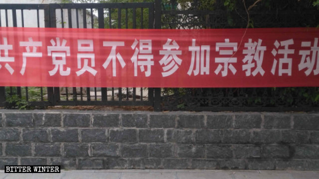 En una calle de Shangbali, un poblado bajo la jurisdicción de la ciudad de Huixian, en la provincia de Henán, se exhibe una pancarta en la cual se les prohíbe a los miembros del Partido participar en actividades religiosas.
