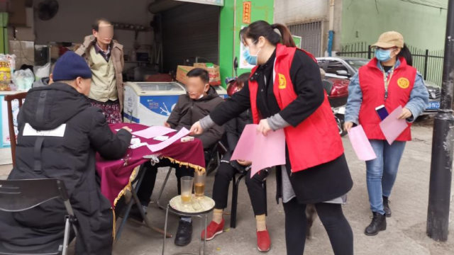 En el distrito de Liunan de la ciudad de Liuzhou, en la Región Autónoma Zhuang de Guangxi, miembros del personal comunitario le entregan a la gente folletos sobre prevención de la epidemia y religión.