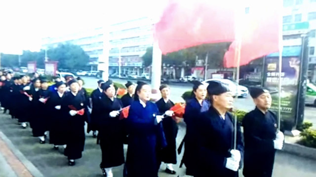Sacerdotes taoístas ondean banderas nacionales y cantan canciones rojas en un desfile efectuado en Ruzhou.