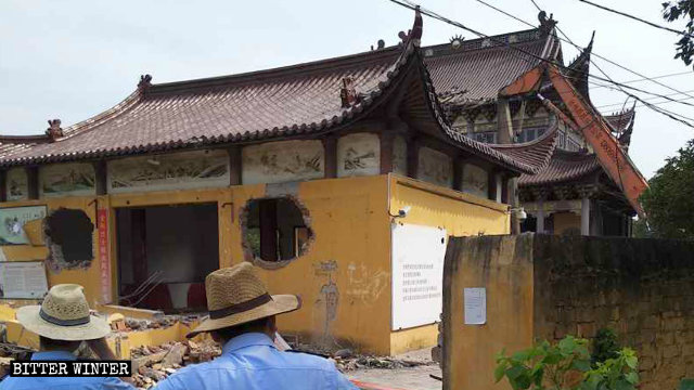 Trabajadores contratados por el Gobierno están demoliendo el Templo de Fuyuan con una excavadora.