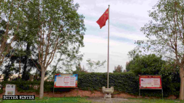 La bandera nacional y tablones de anuncios que promueven leyes relacionadas con la religión y la constitución china en el templo de Cao’an.