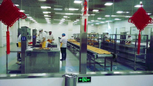 Varios uigures están elaborando pan naan en el parque cultural-industrial.